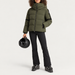 Fusalp women's Barsy II Ski Jacket in Moss Green, full outfit on model holding a ski helmet.