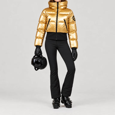 Goldbergh women's Bombardino Ski Jacket in Rich Gold – ski pose view. AI-generated from manufacturer imagery.