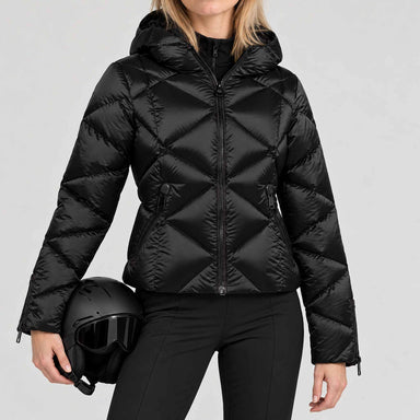 Goldbergh women's Harumi Ski Jacket in Black – model ski pose holding a black helmet, plain cuffs without fur. AI-generated from manufacturer imagery.